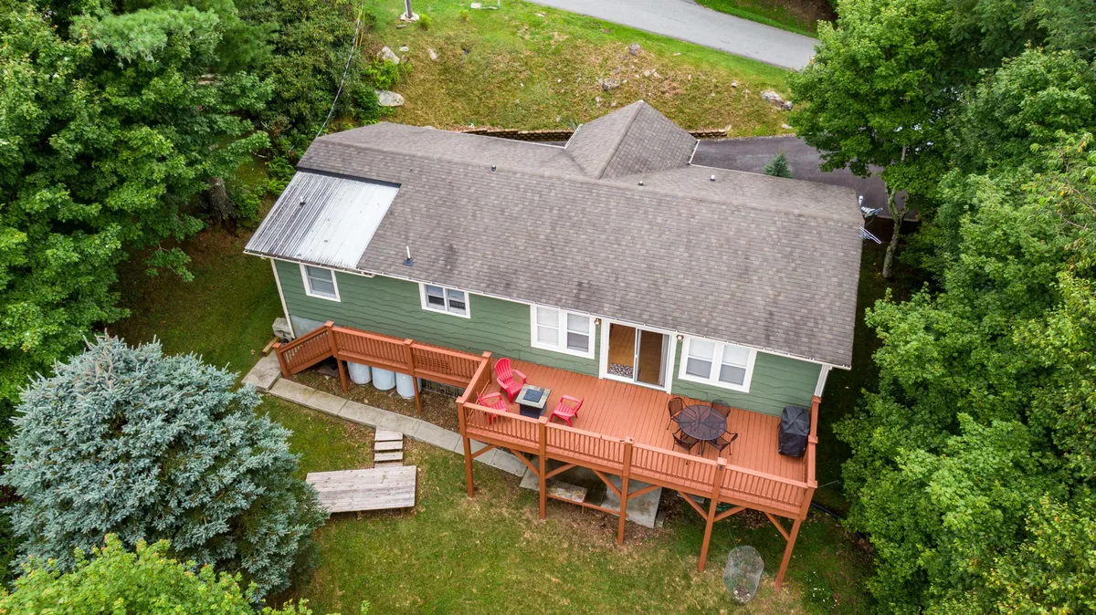 A welcoming wooden deck featuring red chairs set against the green exterior of the house, opening out to the fresh mountain air. The setup suggests a perfect spot to relax after outdoor activities or to gather before a day of adventure, with hints of mountain views beyond.
